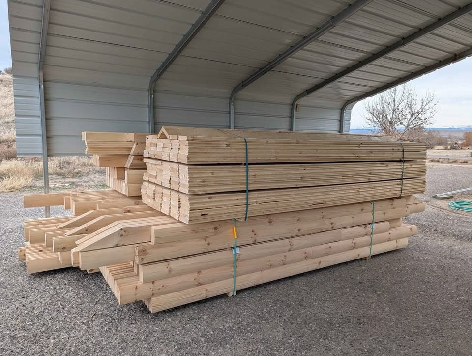 Prefab cabin kit lumber organized and stacked under shelter ready for delivery
