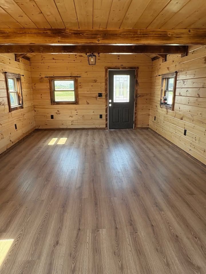 Log cabin entryway with dark entry door, decorative glass insert, and natural wood walls